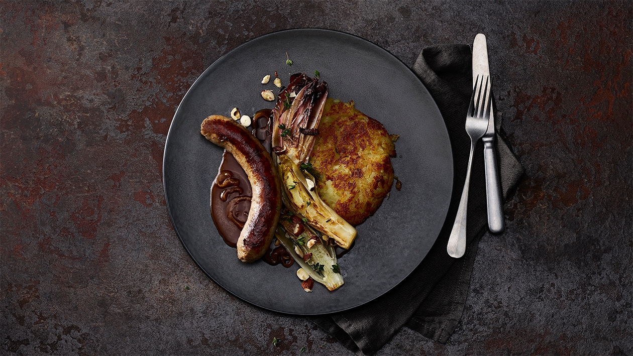 Selbstgemachte grobe Bratwurst mit Zwiebeljus, Rösti und Radicchio Rosso