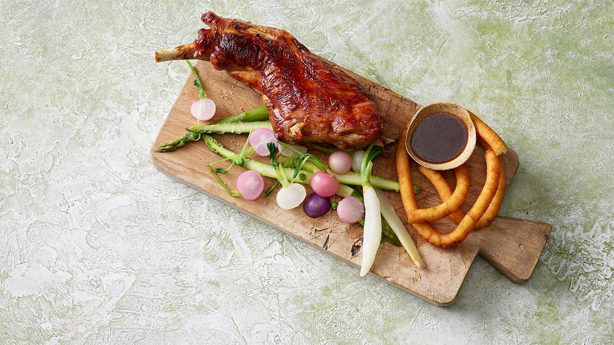 Gitzischlegel mit Rotweinsauce, knusprige Kartoffelkringel und Frühlingsgemüse