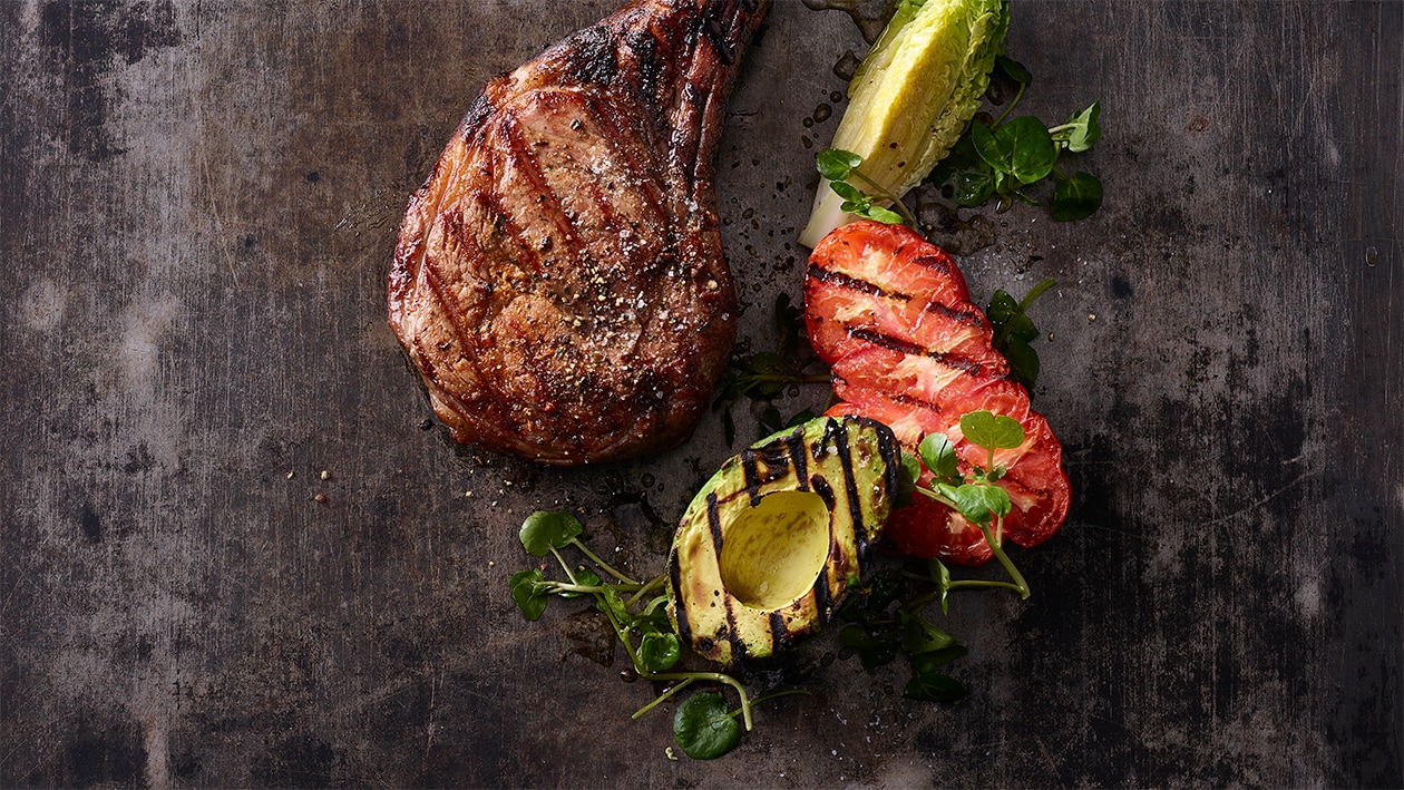 Grilliertes Tomahawk-Steak mit Tomaten und Avocado vom Grill