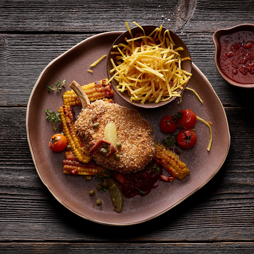 Paniertes Schweinskotelette mit Sauce Portugaise, Pommes allumettes und sautierten Maisstreifen
