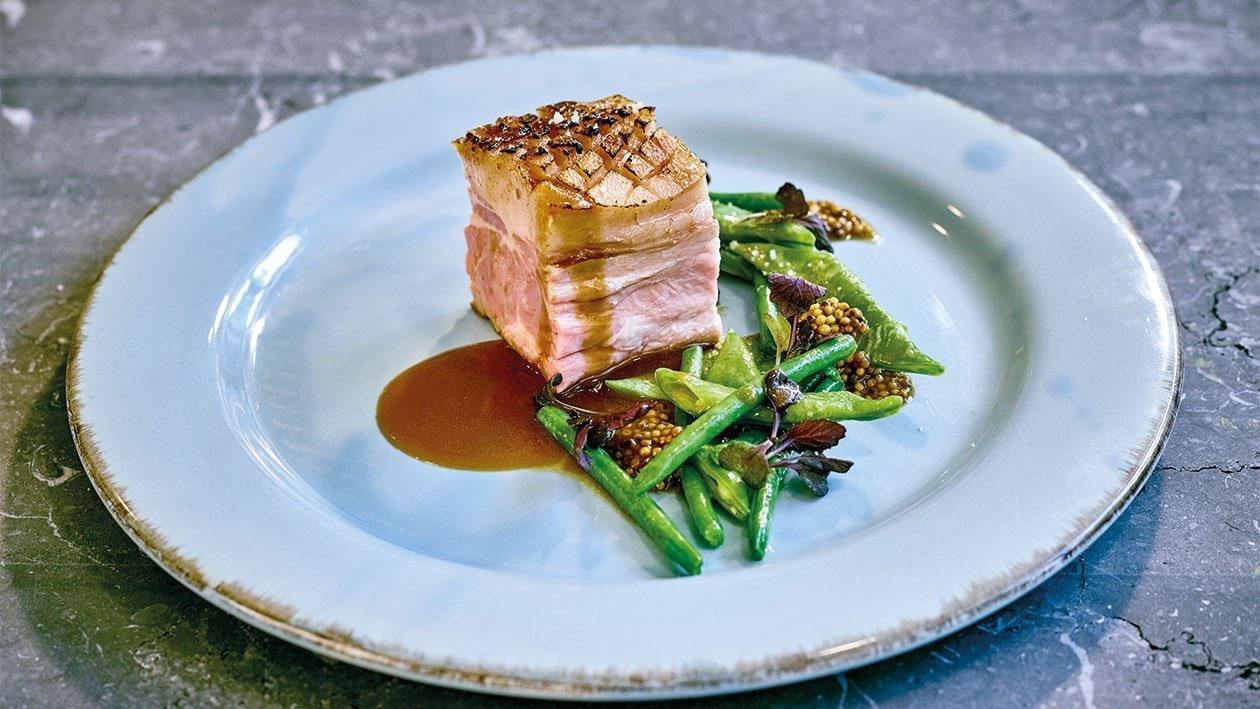 Carré de cochon de lait au jus de poire et moutarde servi avec des haricots verts