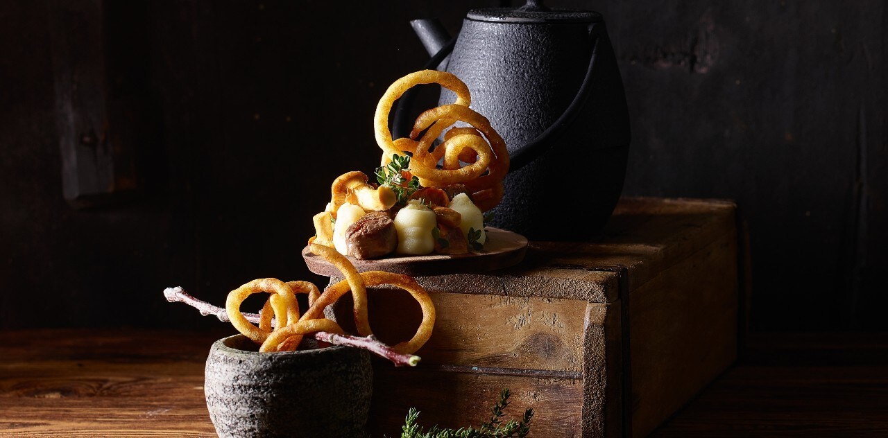 Essence de gibier avec des beignets de pommes de terre à l'entonnoir, des dés d'entrecôte de cerf et des chanterelle